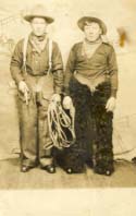 2 men, one with gun and rope, other in chaps postcard 1913